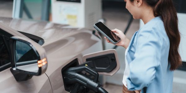 Woman using phone while charging electric car.