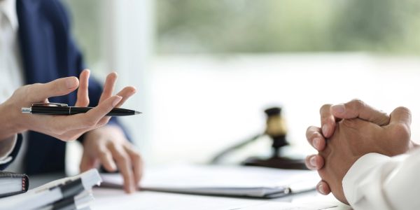 Two people in a legal consultation with a gavel on the table.