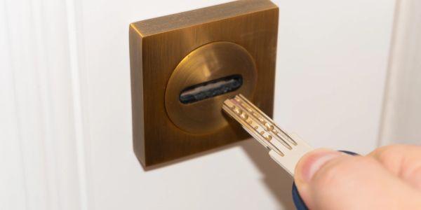 Hand inserting key into a brass lock.