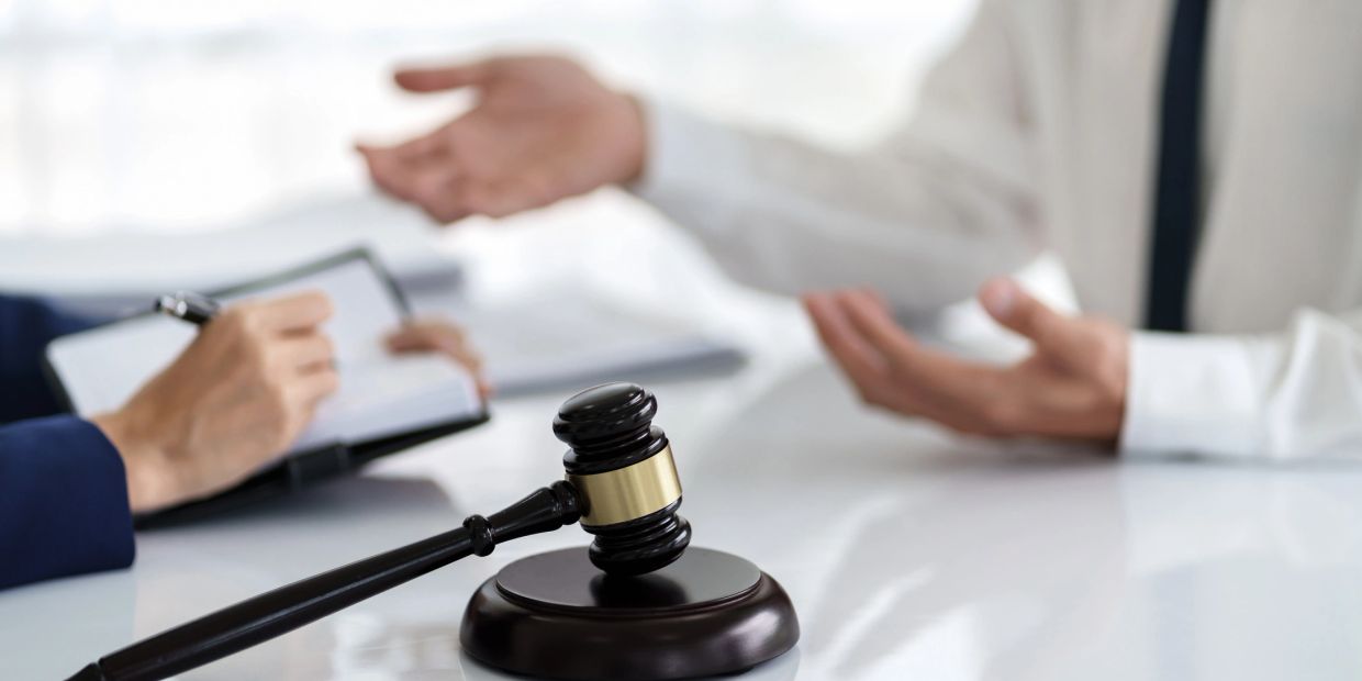 Gavel on table with people discussing.