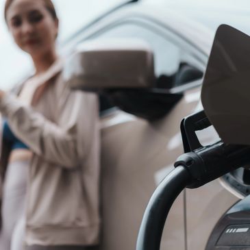 Electric car being charged with a woman in the background.