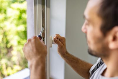 Man repairing or installing a window lock.