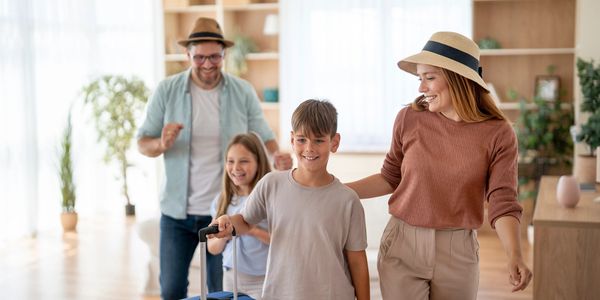 Family joyfully walking with luggage indoors.