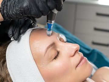 Woman getting a facial treatment with a device.
