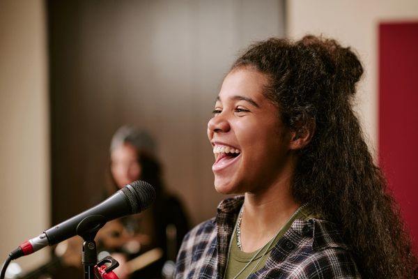 Young woman singing into a microphone with joy.