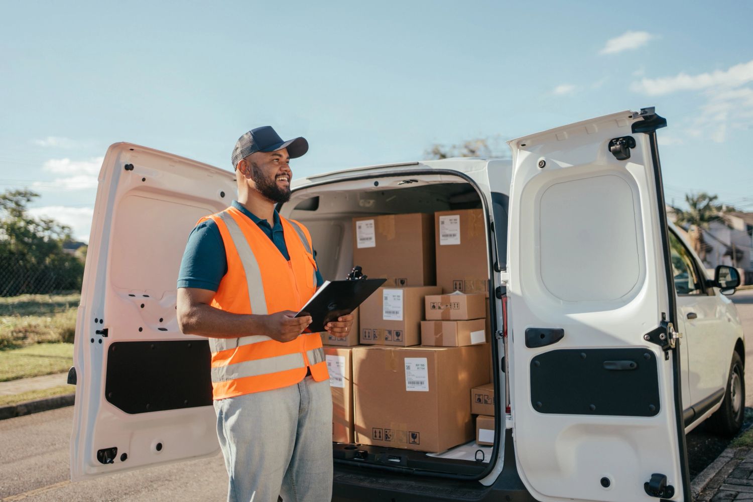 Delivery man with clipboard by a van filled with packages.