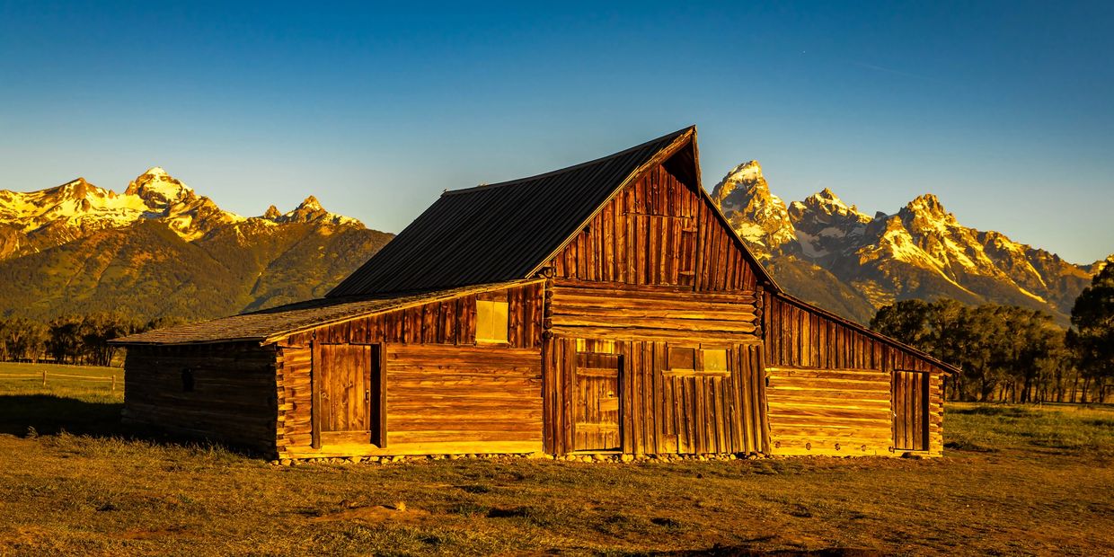 Rustic wooden barn with mountains in the background.