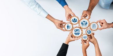 Diverse hands holding interconnected gears with business icons.