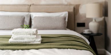 Cozy bed with neatly folded towels and a green blanket.