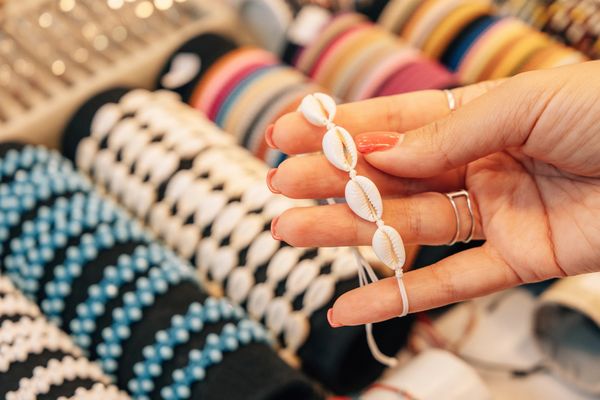 Hand holding a seashell bracelet with bracelets in the background.