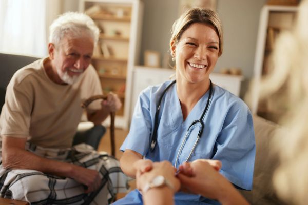 Nurse smiling and holding patient's hands.