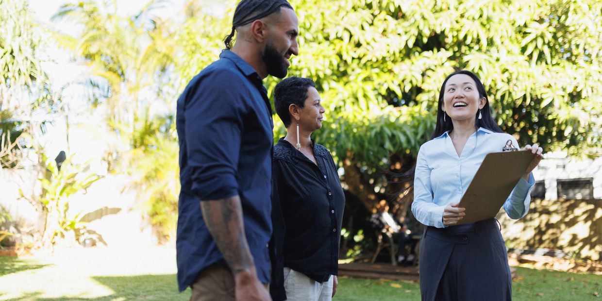 Three people talking outside on a sunny day.