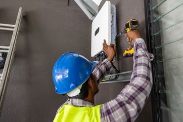 Electricians installing a wall mounted solar inverter and electrical connections.