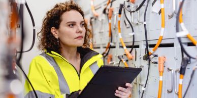 Woman inspecting electrical equipment with a tablet.