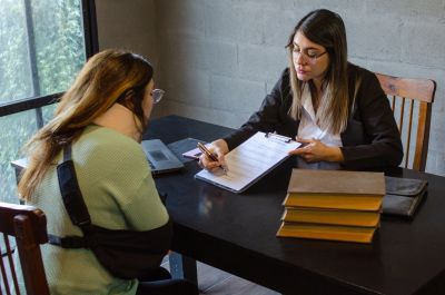 Woman consulting another woman with arm in sling.