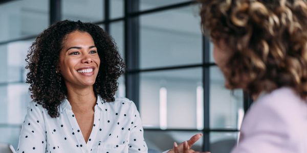 Two smiling business women discussing their next tax hire