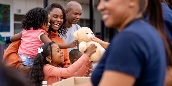 Family happily receiving a teddy bear at a donation event.