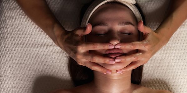 Person receiving a facial massage with hands on their face.
