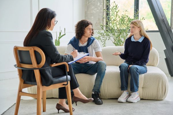 Couple in therapy session with female therapist.