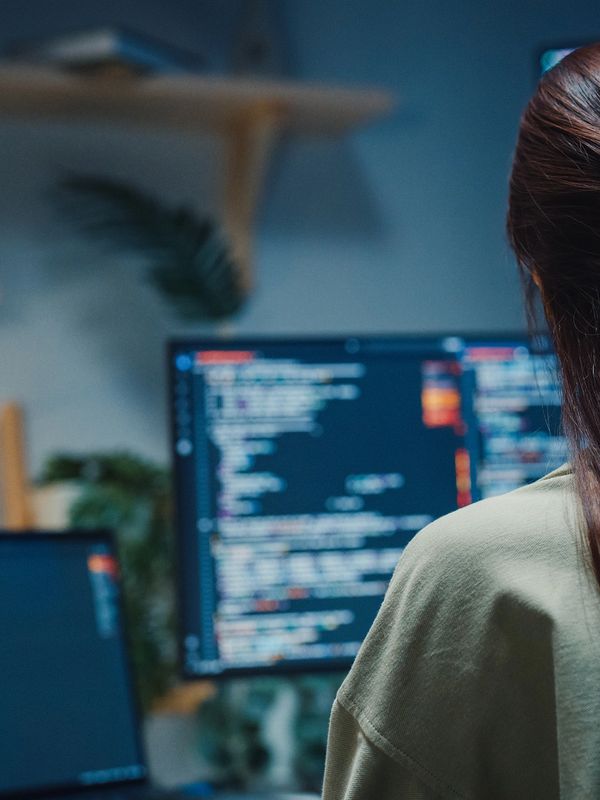 Person coding on multiple computer screens.