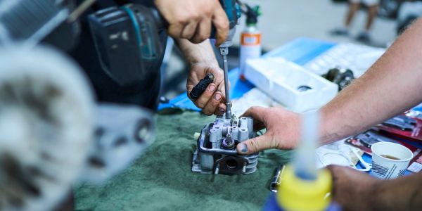 Hands repairing a mechanical device with a screwdriver.