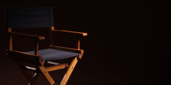 Wooden director's chair with black fabric seat and back.
