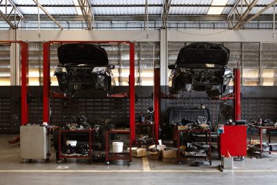 Two cars lifted in a repair garage with open hoods.
