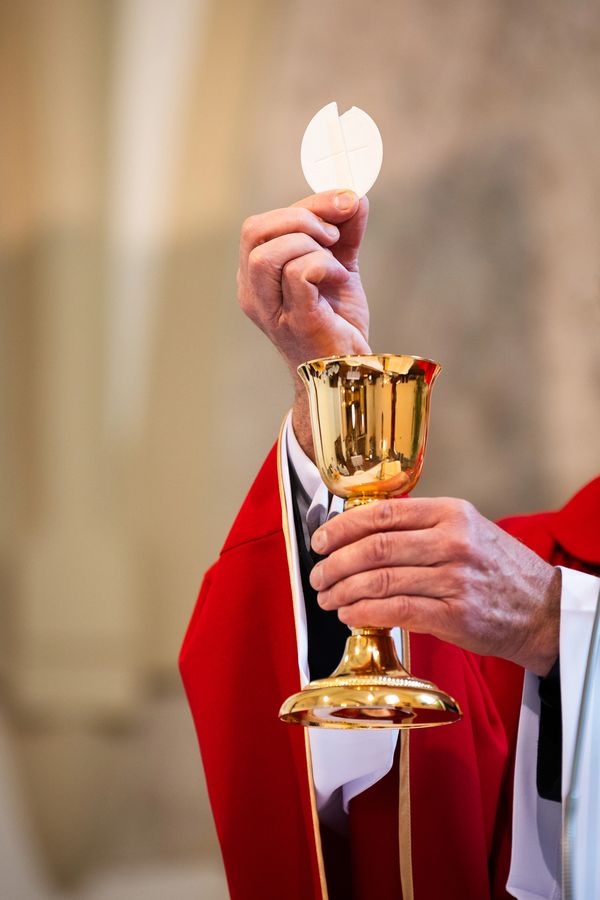 Priest holding communion wafer and chalice.