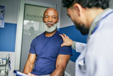 Doctor reassuring an elderly man during a consultation.