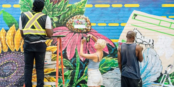 People painting a colorful mural on a brick wall.
