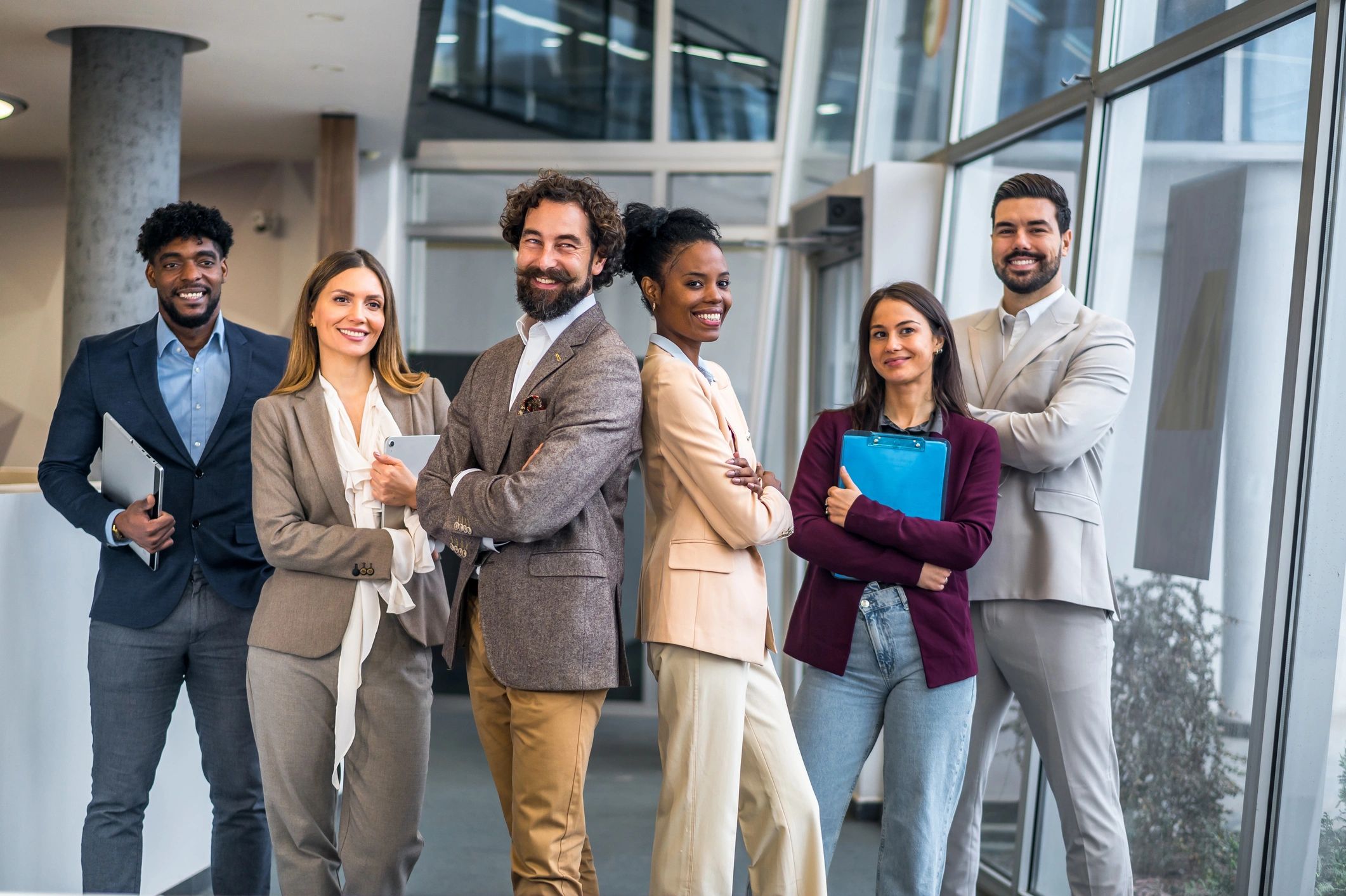 Diverse group of professionals smiling in office hallway.