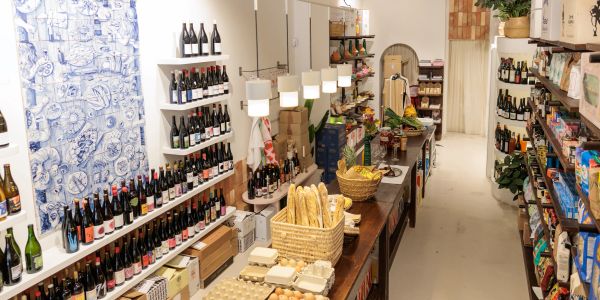 Cozy shop aisle with wine bottles and fresh bread baskets.