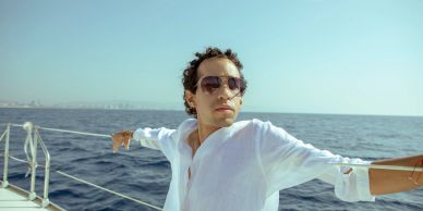 Man in sunglasses enjoying a boat ride under clear skies.