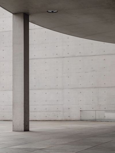 Minimalist concrete structure with a pillar and curved ceiling.