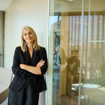 Female media and public relations executive standing confidently in a modern corporate office.