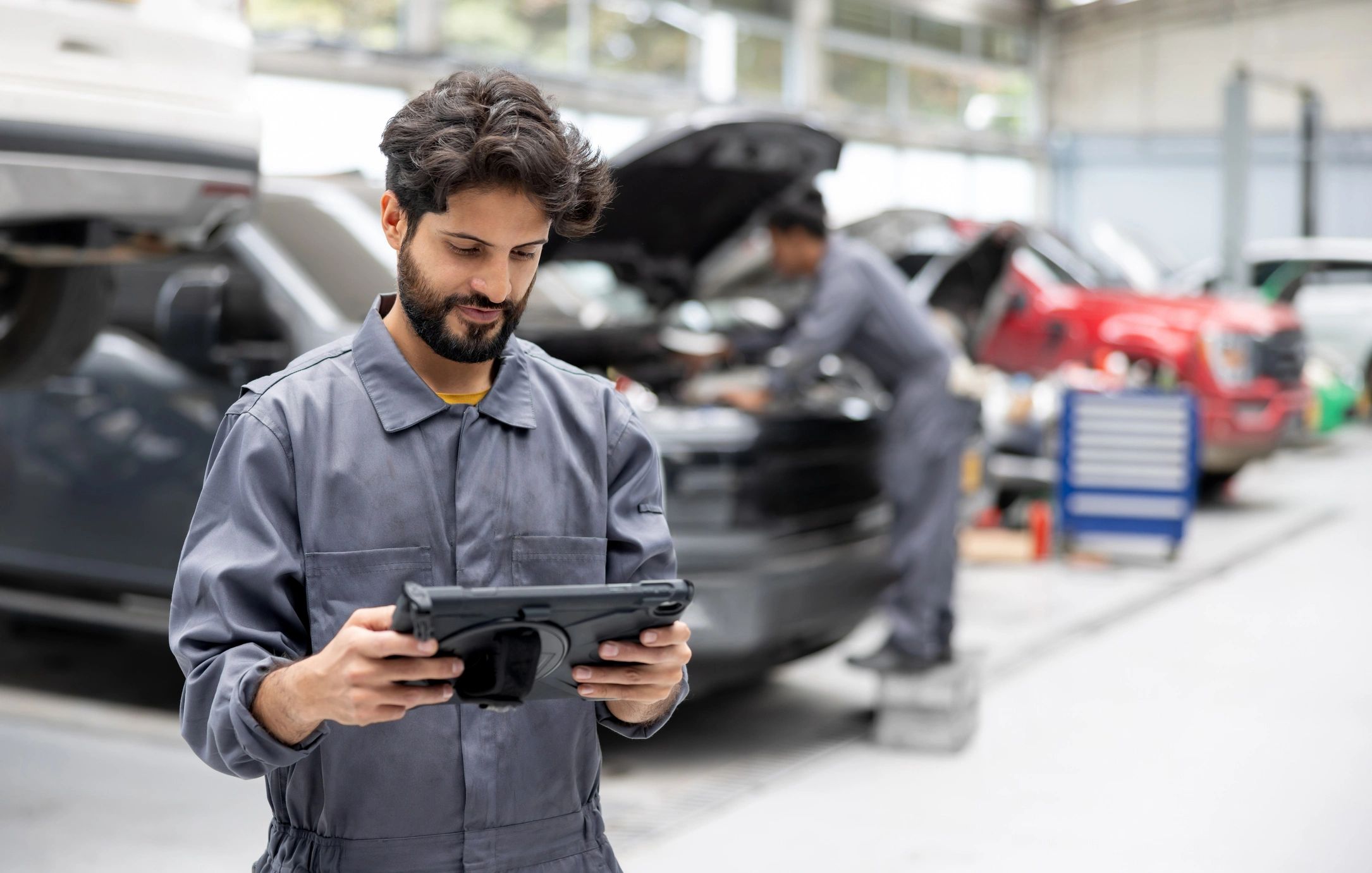 Automotive technician using a tablet in a repair shop.