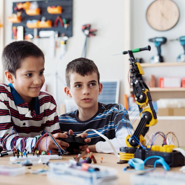 Two boys working on a robotic arm project.
