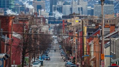 Pittsburgh neighborhood street with rowhouses and the downtown skyline