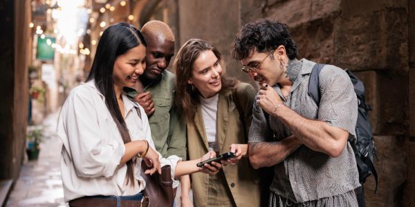 Group of diverse friends looking at a phone in an alley.