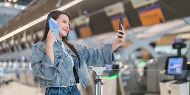 Woman taking selfie with phone and passport.