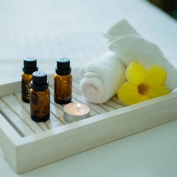 Spa essentials with oils, towel, candle, and flower.