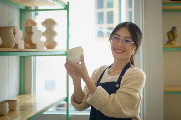 Young woman holding a ceramic piece in a pottery studio.