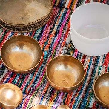Set of singing bowls and a drum on a colorful cloth.