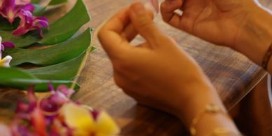 Hands arranging flowers on a wooden table.