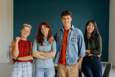 A group of four young adults smiling together.