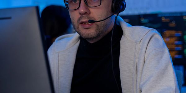 Man with headset working on a computer at night.
