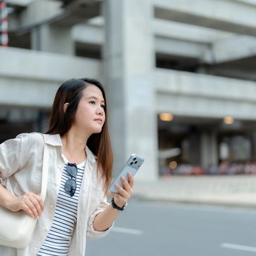 Woman holding a smartphone looking into the distance.