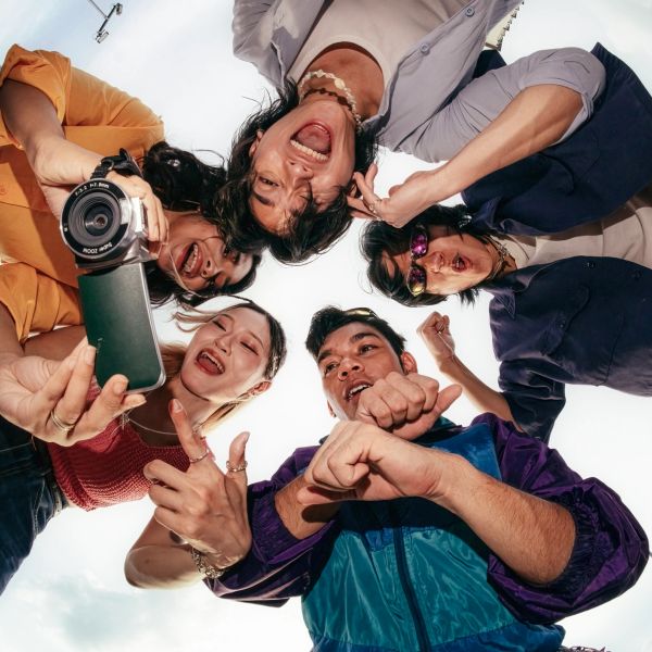 Group of friends taking an energetic selfie from below.