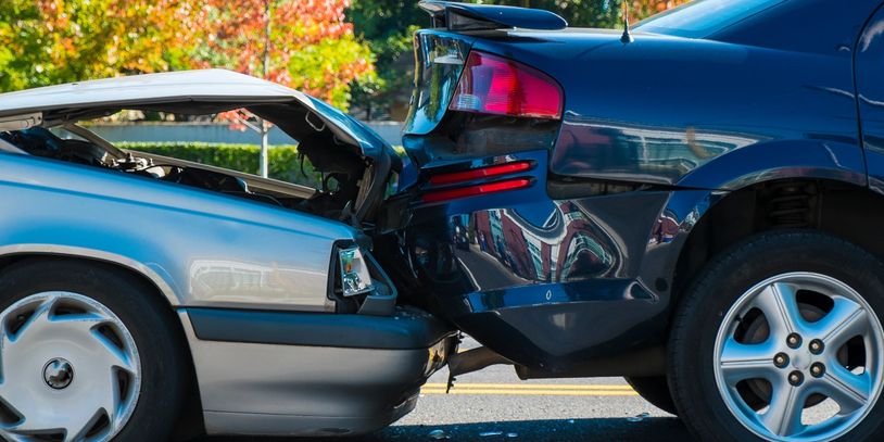 Two cars involved in a rear-end collision on a sunny day.