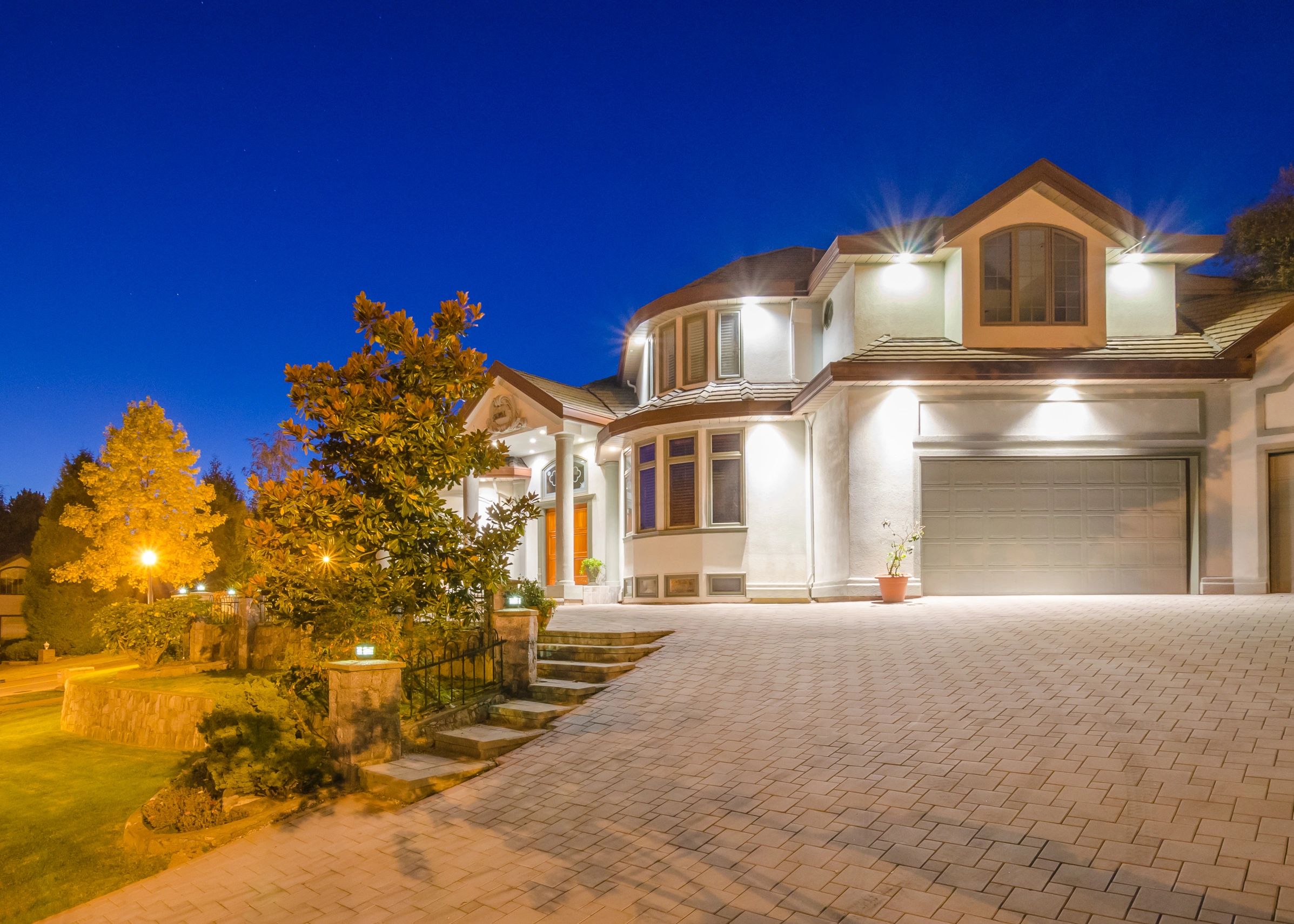 Luxurious house lit up at night with clear sky.